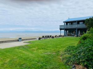 a building on the beach with chairs on the grass at Sand Pebbles Inn in Qualicum Beach