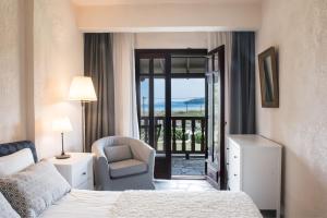 Un dormitorio con una cama y una silla y una ventana. en White Blossom Villa #Fourka, en Skála Foúrkas