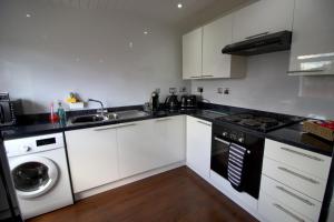 a kitchen with white cabinets and a sink and a dishwasher at The Marlfield in Bellshill