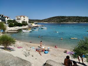 un grupo de personas en una playa con barcos en el agua en Apartment Tomo, en Ražanj