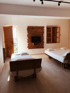 a bedroom with two beds and a flat screen tv at Old Town Hotel Dhermi in Dhërmi