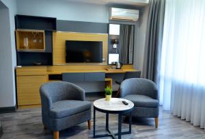 a living room with two chairs and a tv at Hotel Konak in Momchilgrad