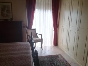 a bedroom with a bed and a chair and a window at Ai piedi del Vulcano in Gravina di Catania