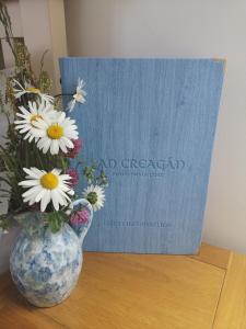 un jarrón de flores sentado en una mesa con un libro en An Creagán Bed and Breakfast en Inisheer