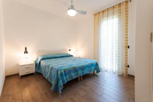 a white bedroom with a bed and a night stand at Le Primule in Rosolina Mare