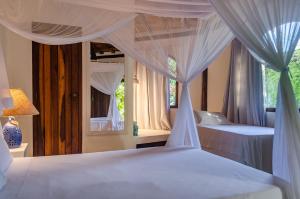 a bedroom with two beds with curtains and a window at Pousada Villa Bahia in Trancoso