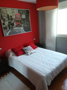 a bedroom with a bed with a red wall at Apartamento A Atalaia in Laxe