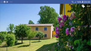 a house in a yard with trees and purple flowers at hotel das deichhaus in Gorleben