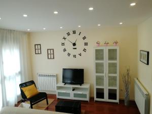 a living room with a clock on the wall at Coqueto apartamento Las Margas Golf in Sabiñánigo