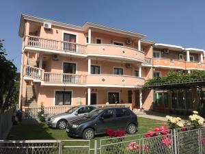 two cars parked in front of a pink building at Rooms Ibrocevic in Ulcinj +18 photos
