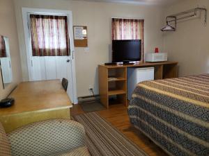 a hotel room with a bed and a desk with a television at Regent Motel in Saint John