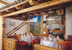 a restaurant with tables and chairs and a painting on the wall at Hotel des Alpes in Molveno