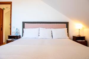 ein Schlafzimmer mit einem großen Bett mit weißer Bettwäsche und Kissen in der Unterkunft Lagar do Sapateiro in Fontes