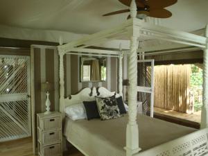 a bedroom with a white bed with a ceiling fan at Hidden Cove Eco Retreat in Luganville