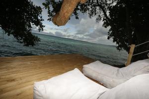 zwei weiße Kissen auf einem Deck neben dem Wasser in der Unterkunft Hidden Cove Eco Retreat in Luganville