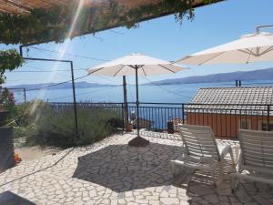 un patio con dos sillas y una sombrilla en Apartment Little princess Dora, en Senj
