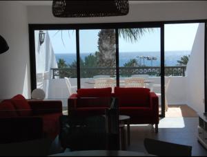 ein Wohnzimmer mit roten Stühlen und Blick auf das Meer in der Unterkunft Bonito y espacioso apartamento al lado de la playa. in Tías