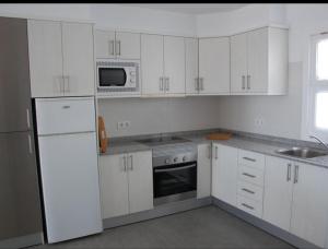 eine weiße Küche mit weißen Schränken und einer Mikrowelle in der Unterkunft Bonito y espacioso apartamento al lado de la playa. in Tías
