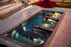 a pool with chairs and an umbrella in it at Hotel Maritur - Adults Only by Pierre & Vacances in Albufeira