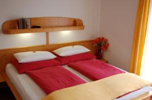 a bed with red and white pillows on it at Sommereck Appartements in Seeboden