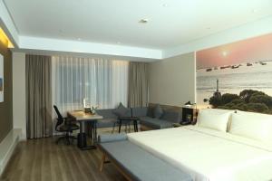 a hotel room with a large bed and a living room at Atour Hotel (Nantong Zhongcheng) in Nantong