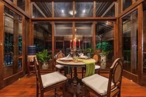 a dining room with a table and chairs and windows at Villa Mulyono in Batu