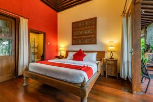 een slaapkamer met een groot bed met rode muren bij Villa Mulyono in Batu
