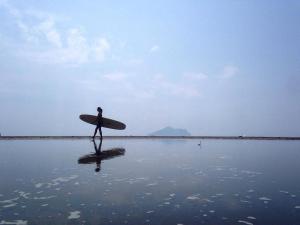 頭城的住宿－宜蘭海天濱海休閒民宿，一个人在海滩上用冲浪板行走