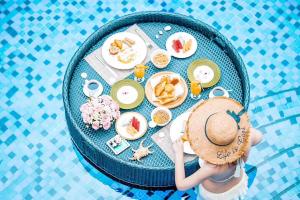 三亞的住宿－三亚悦榕庄(私享沙滩，早餐至14点)，坐在餐桌旁带食物的戴帽子的女人