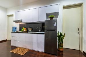 a kitchen with white cabinets and a stainless steel refrigerator at Villa Mulyono 2 in Batu