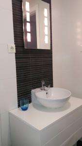 een badkamer met een witte wastafel en een spiegel bij Apartamento playa canet d'en Berenguer in Canet de Berenguer