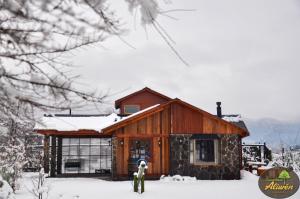 a cabin in the snow with a person standing in front of it at Condominio Aliwén Cabañas in Malalcahuello