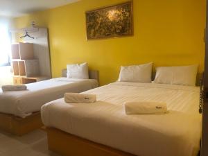 two beds in a room with yellow walls at The Seven Luck in Bangkok