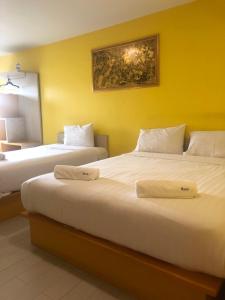 two beds in a hotel room with yellow walls at The Seven Luck in Bangkok