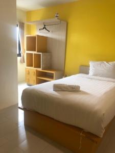 a bedroom with a large white bed with a yellow wall at The Seven Luck in Bangkok