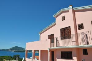 a pink building with a view of the water at Apartments Villa Luka in Sveti Stefan