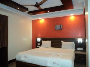 um quarto com uma cama grande e uma parede vermelha em Mani's residency em Madurai