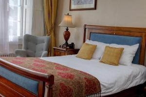a bedroom with a bed with a chair and a lamp at Best Western Henbury Lodge Hotel in Bristol