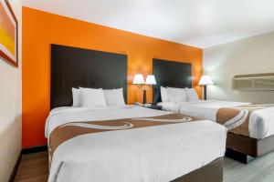 two beds in a hotel room with orange walls at Quality Inn Auburn Campus Area I-85 in Auburn