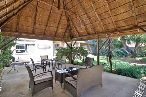a patio with chairs and tables and a wooden umbrella at Fin and Feather Guest Lodge in Boksburg