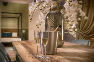 una mesa con dos copas de vino y un jarrón con flores en PALAZZO FORLEO Luxury Apartment en Lecce