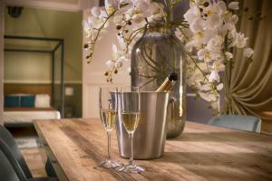 a table with two glasses of wine and a vase with flowers at PALAZZO FORLEO Luxury Apartment - TREB Collection in Lecce