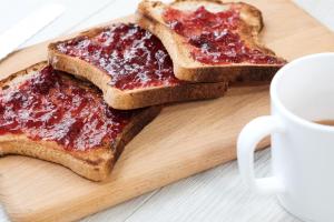 two pieces of toast with jam on a cutting board with a cup of coffee at XOXO Kuta Legian Hostel in Legian