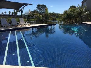 a swimming pool with two chairs and a swimming pool at Cypress Townhouse 11 in Mulwala