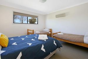 a bedroom with two beds and a blue comforter with white arrows at Cypress Townhouse 11 in Mulwala