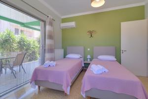 two beds in a room with a balcony at Carpe Diem near the Athens airport in Markopoulo