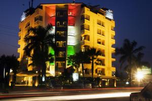 a tall building with palm trees in front of a street at Regenta Orko's Haridwar, Motichur in Haridwār