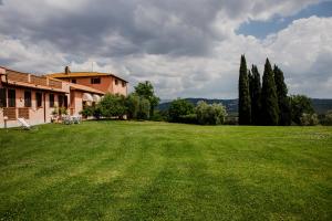 une grande cour verdoyante avec une maison et des arbres dans l'établissement Hotel Relais Santa Genoveffa, à Civitella Paganico