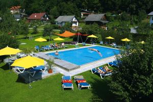 einen Blick über einen Pool mit Stühlen und Sonnenschirmen in der Unterkunft Hotel Restaurant Marko in Velden am Wörthersee