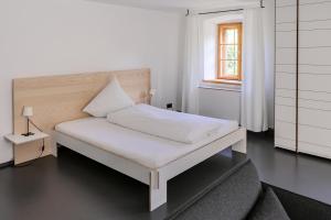 een wit bed in een kamer met een raam bij Gästehaus berge in Aschau im Chiemgau